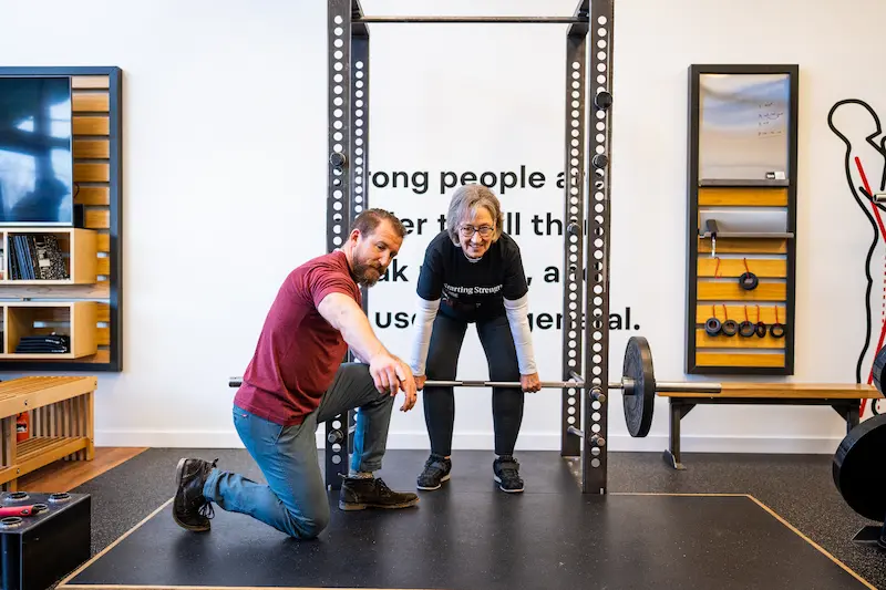 Sylvia being coached in strength training at Starting Strength gym